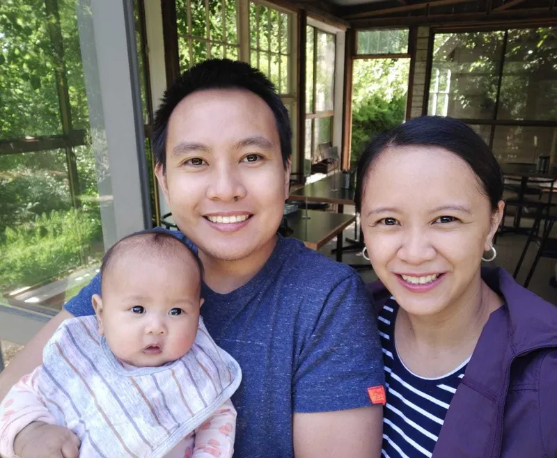 Daniel sitting outside with his wife and baby