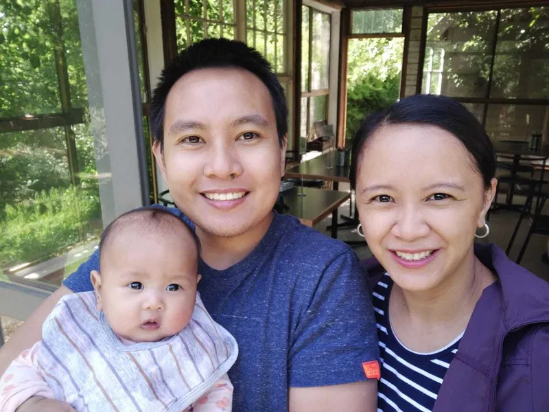Daniel sitting outside with his wife and baby