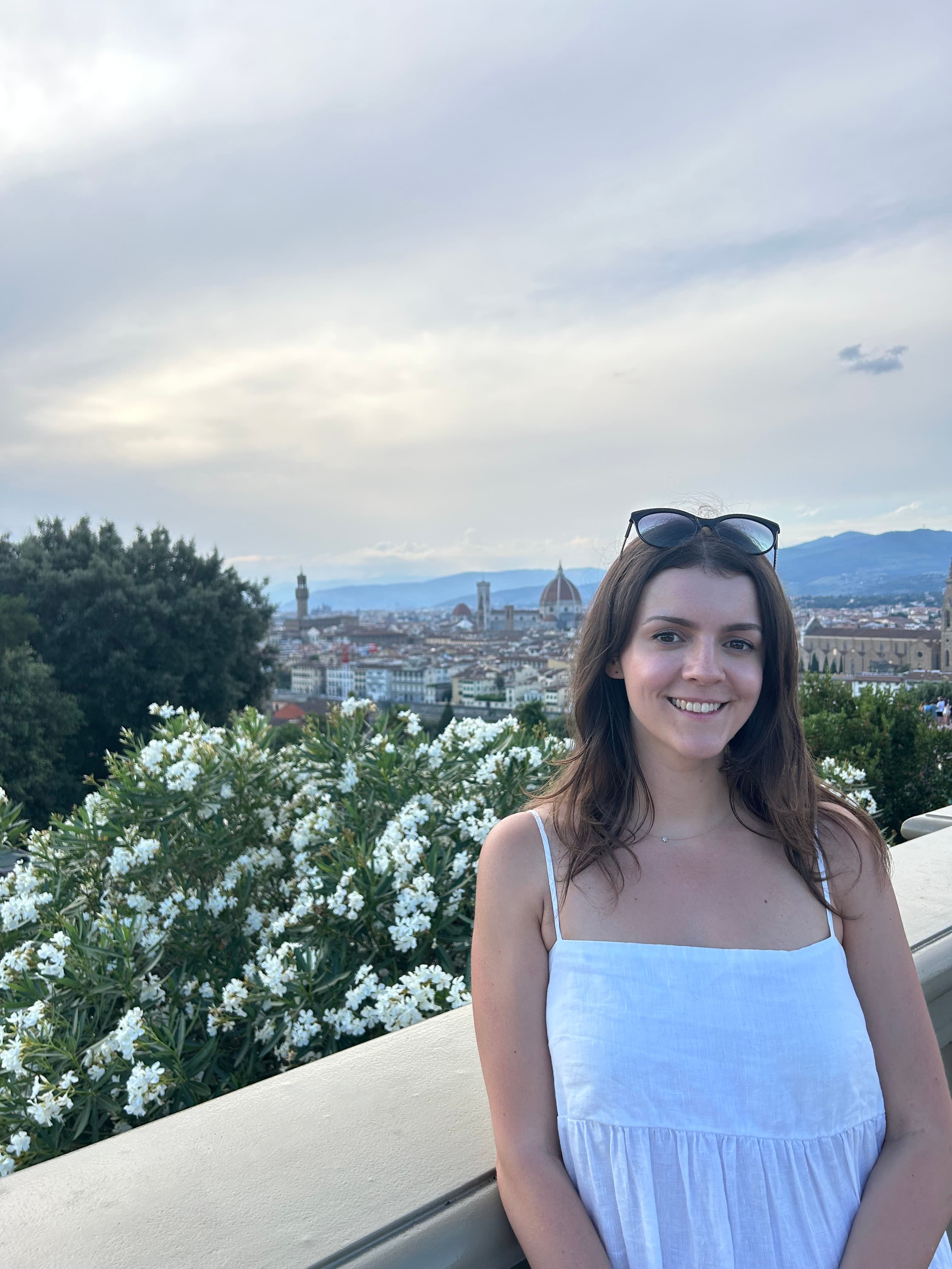 Optimising team member Ellie poses in front of a gorgeous view in a white dress