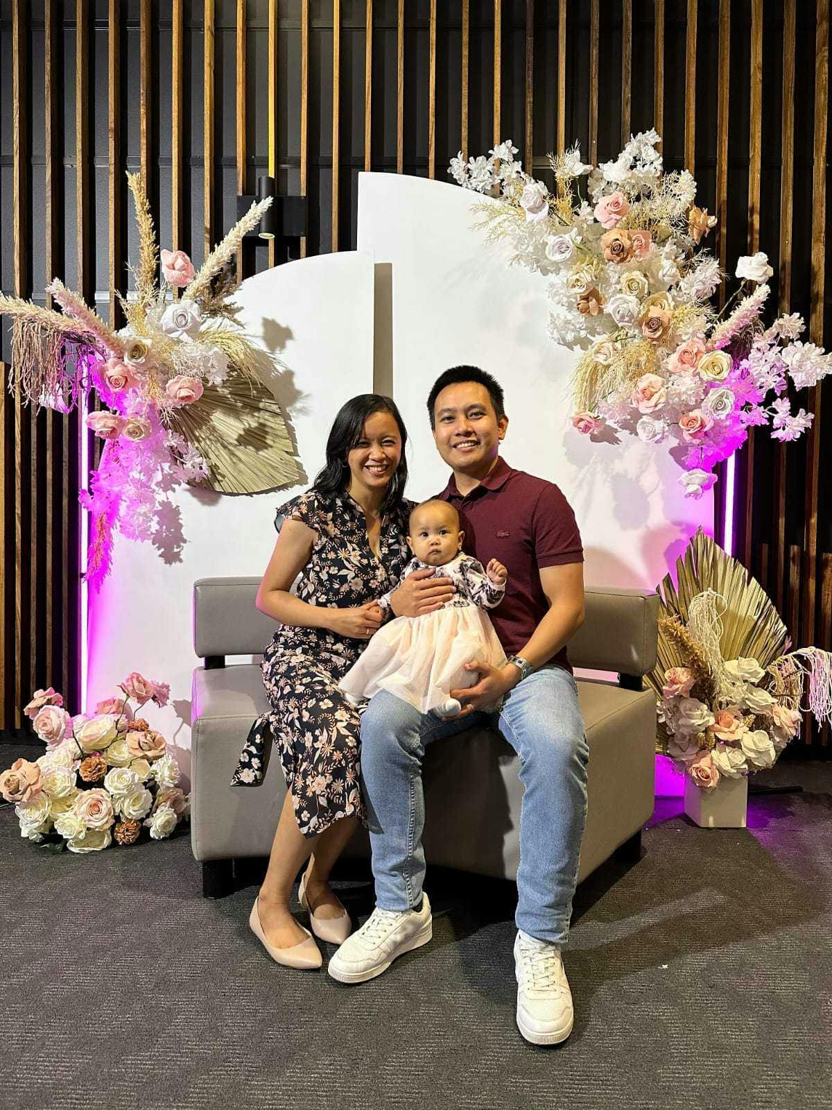 Daniel and his family in front of a floral backdrop