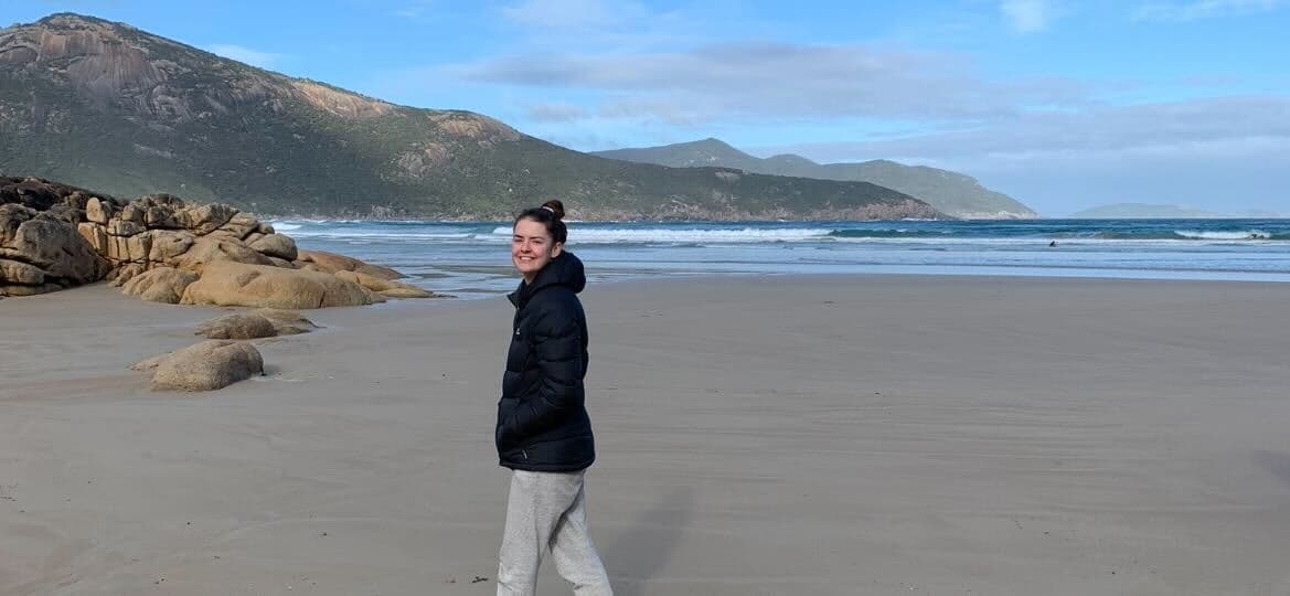 Women in jacket walking along Australian beach