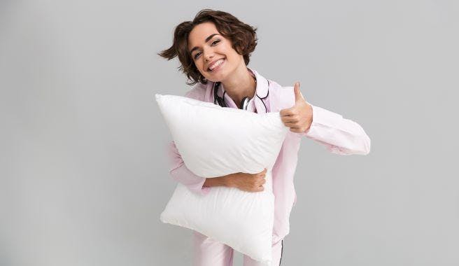 woman holding a pillow and giving thumbs up