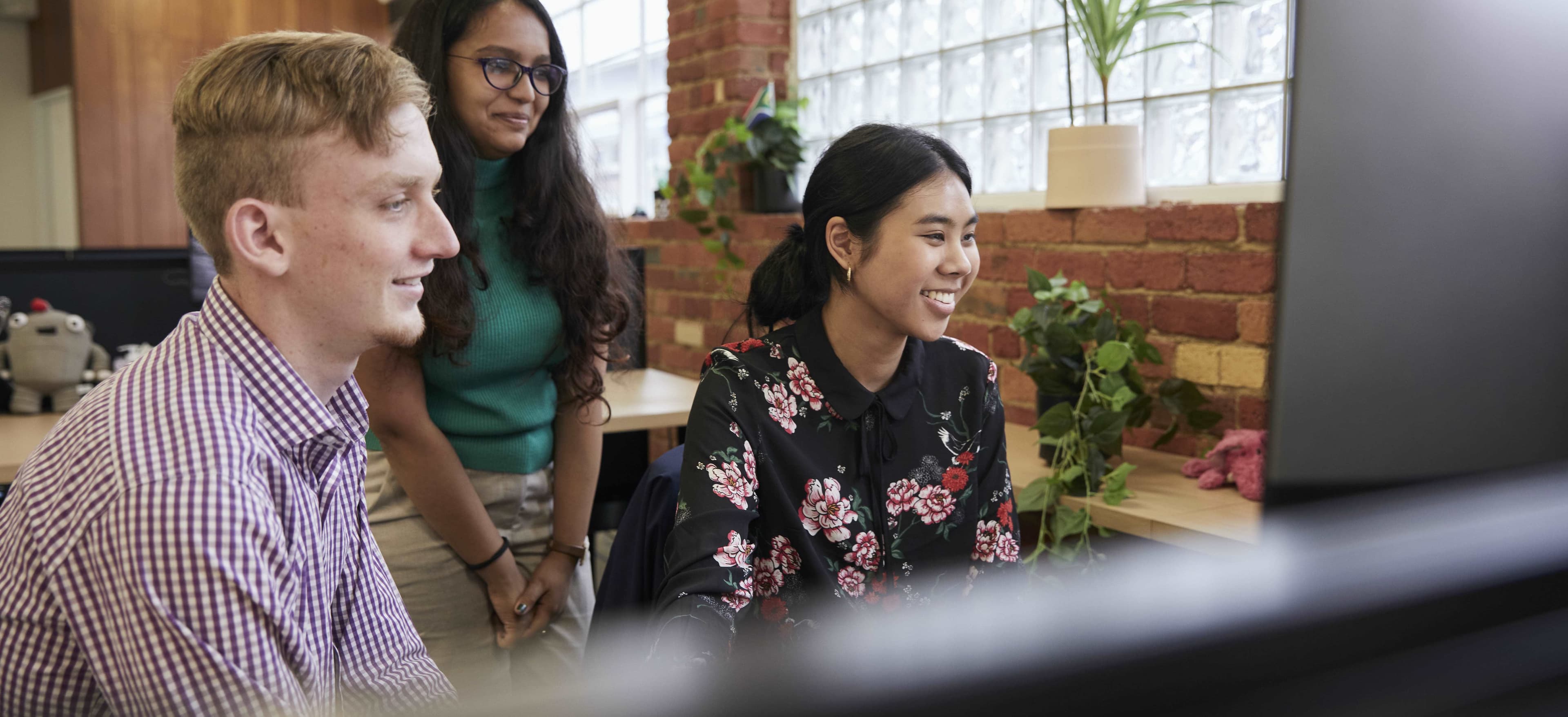 multiple optimising employees huddled around a computer